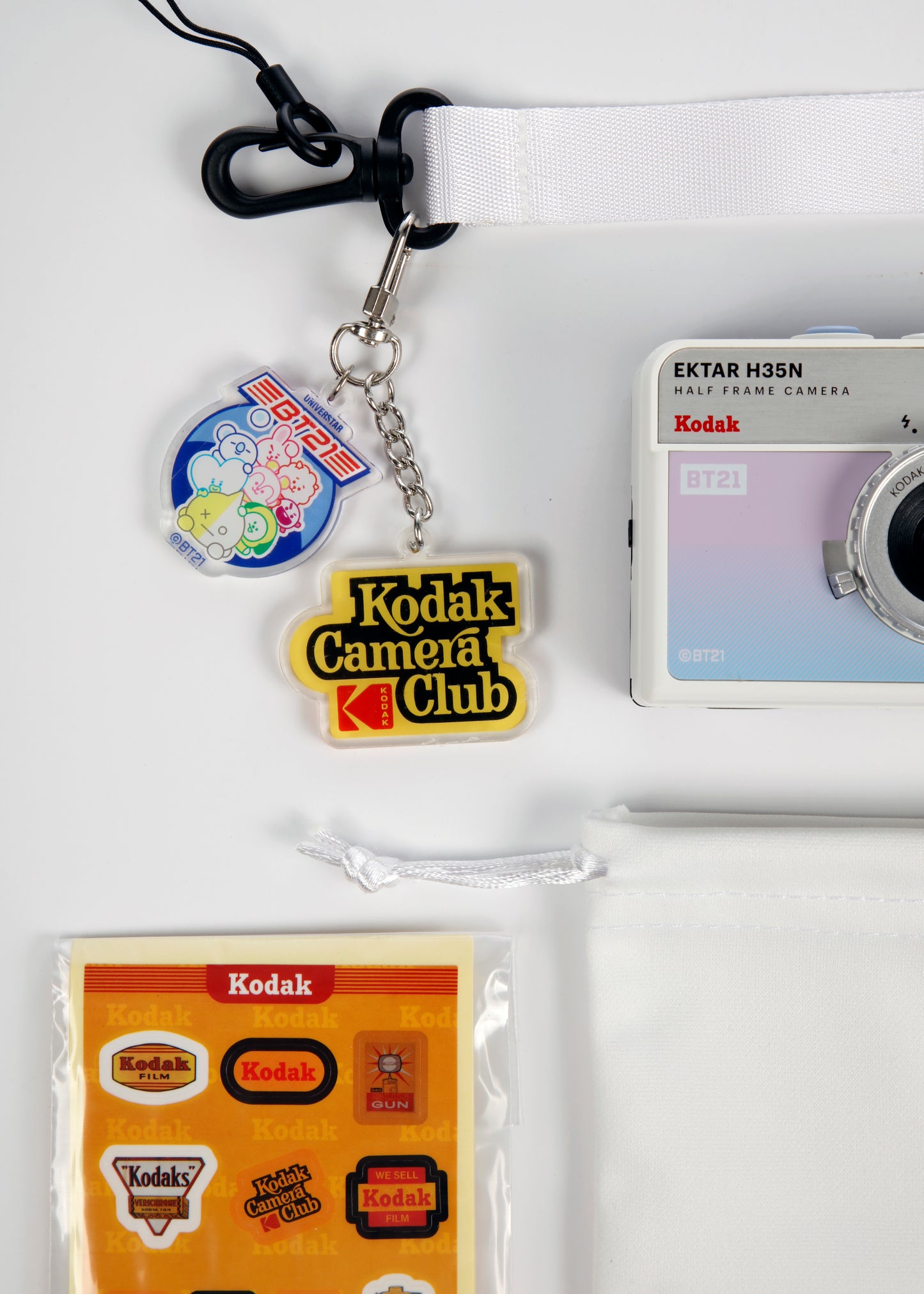 Kodak Ektar H35N BT21 edition half frame camera that includes wrist strap with keychains, traveling case, and a pack of stickers.
