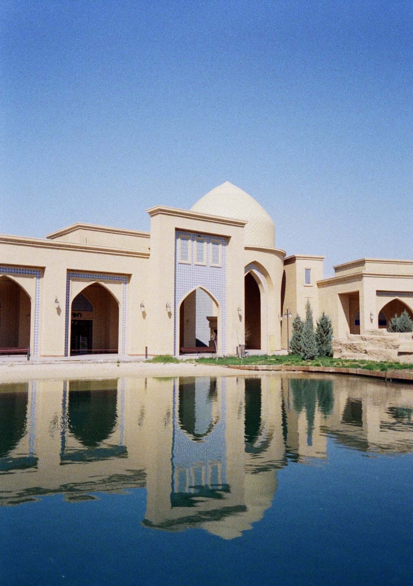 Beautiful architectural reflection of a building by the water under a clear blue sky.