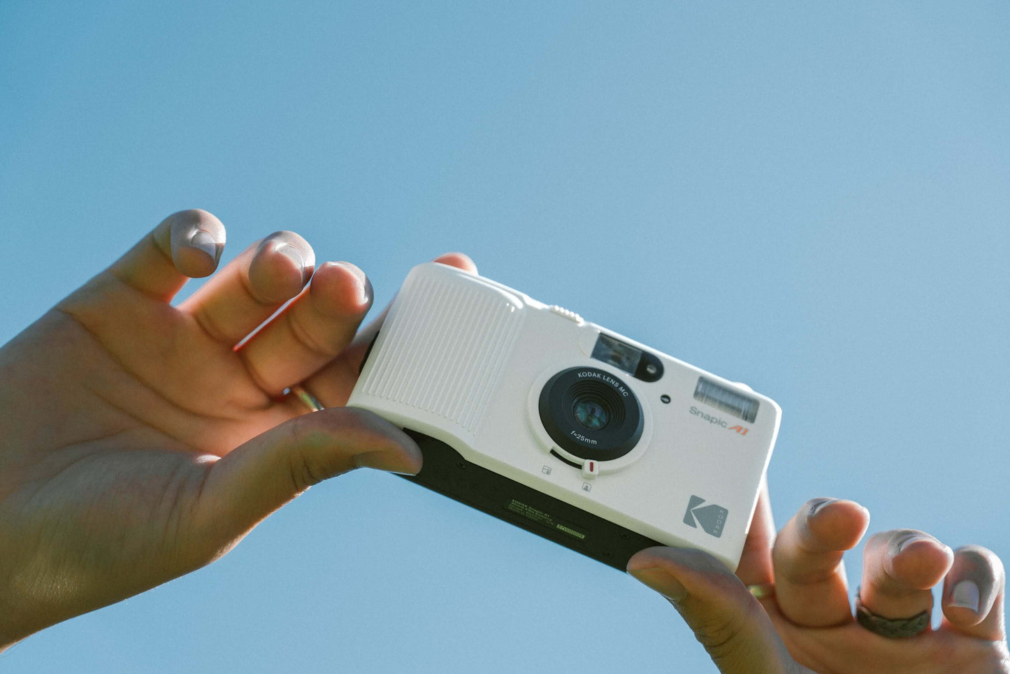 Person's hands holding the Kodak Snapic A1 35mm camera in the sky.