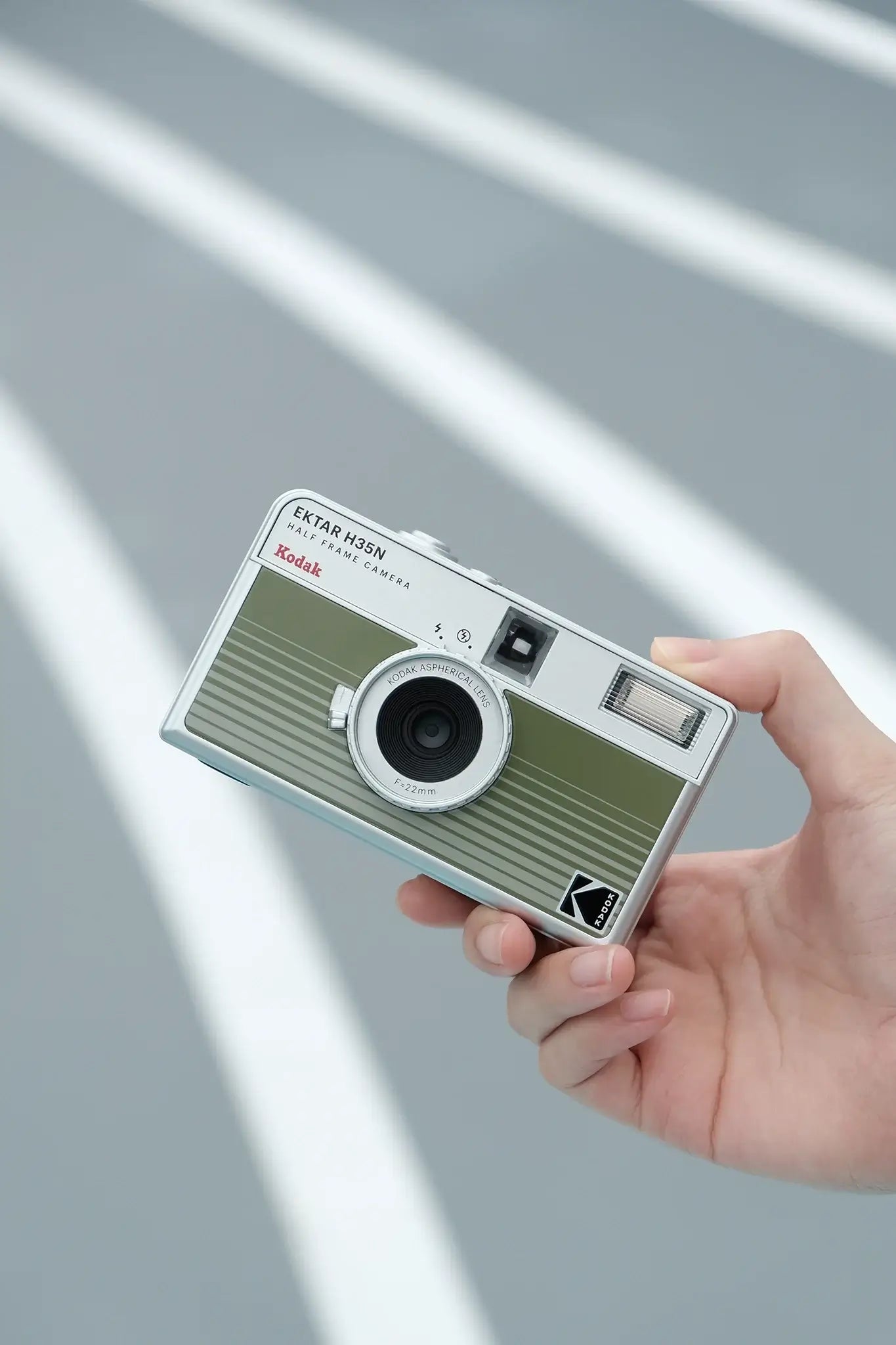 Kodak Ektar H35N Half Frame Film Camera (Green) held in hand against a grey backdrop.