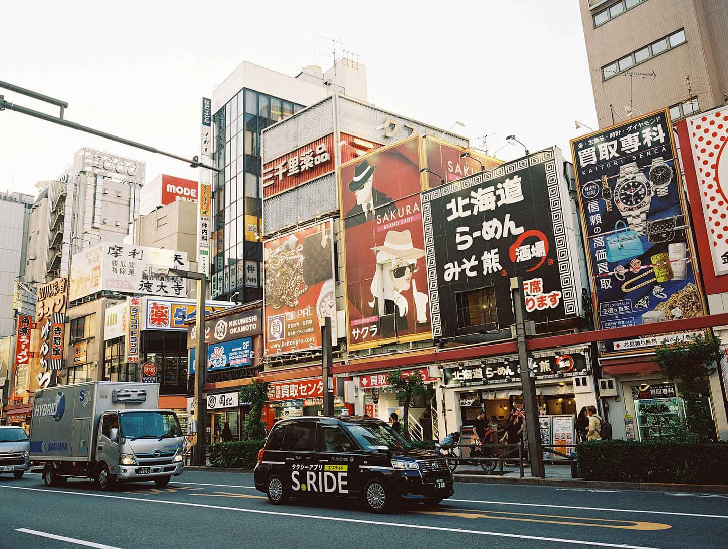 City street view featuring various advertisements and vehicles in an urban setting.