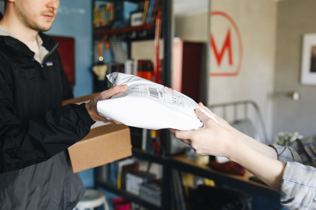 How Film Developing Co's Round Trip Shipping Label is being handed over during a package exchange.