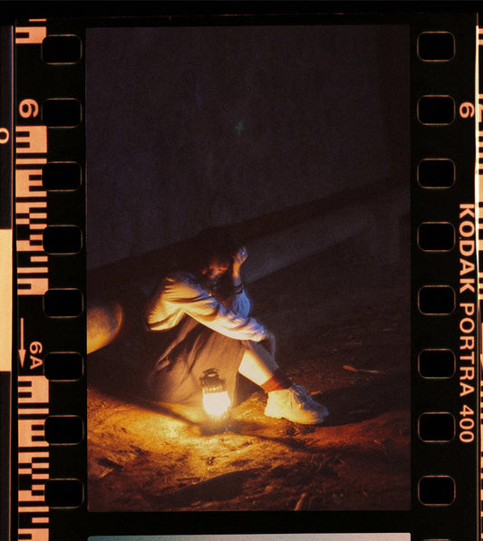 A person sitting in low light with a lantern, showcasing techniques for Low Light Photography.