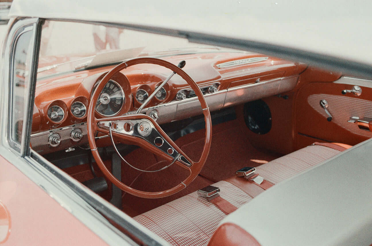 Vintage car interior featuring retro red dashboard and steering wheel, shot on Street Candy Psychedelic Street 400.