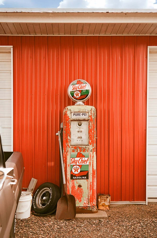 Vintage SkyChief gasoline pump against a red barn wall, showcasing retro design and colors, shot on Flic Film Aurora 800.