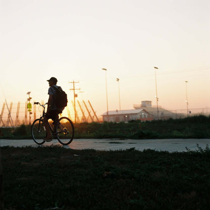 Silhouette of a person riding a bike at sunset with a soft pastel sky in the background shot on Kodak Gold 200.