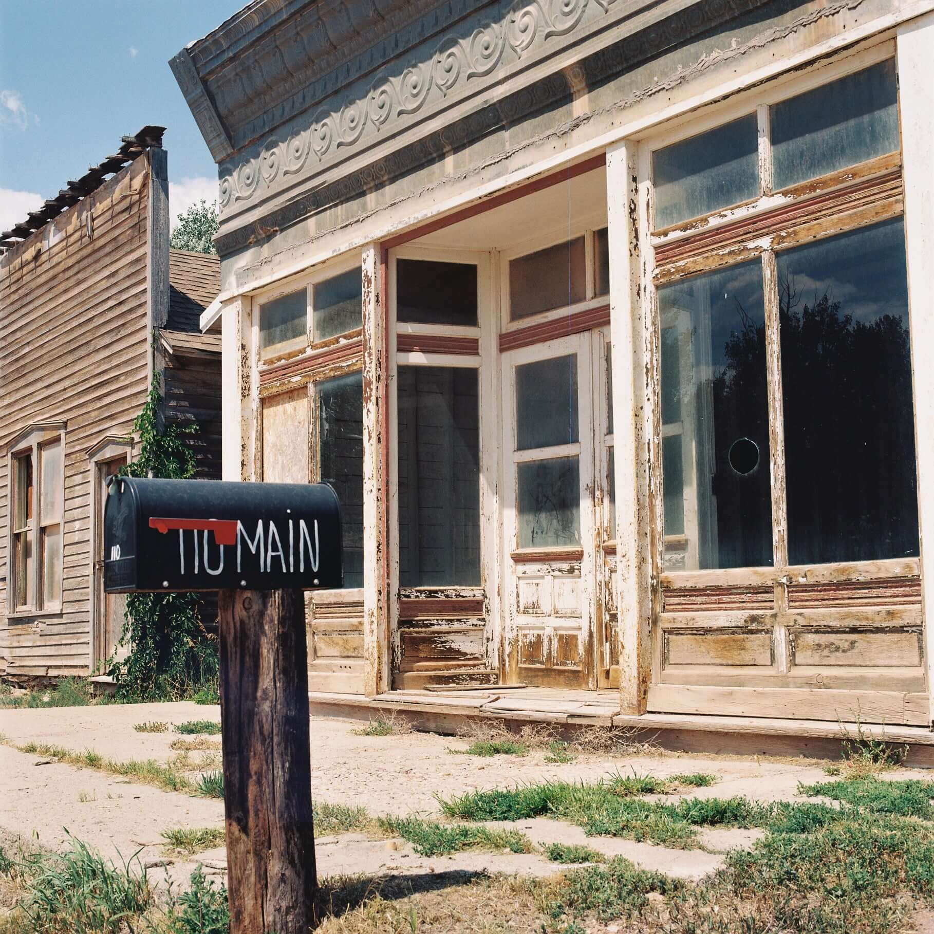 Abandoned building with a vintage mailbox marked '110 Main' in a rustic setting shot on Kodak Gold 200.