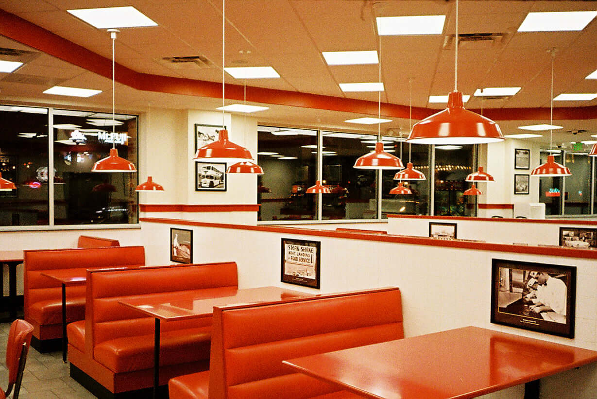 A vibrant diner interior featuring red booths and pendant lights, creating a nostalgic ambiance for diners.