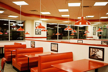 A vibrant diner interior featuring red booths and pendant lights, creating a nostalgic ambiance for diners.