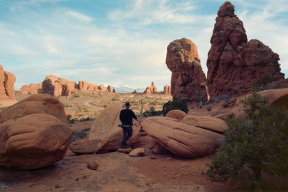 Person exploring natural rock formations in a desert landscape with clear skies.