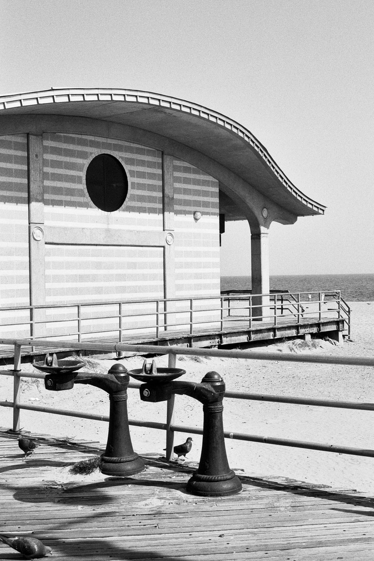 Black and white image of a beachside building with unique architecture and railing.