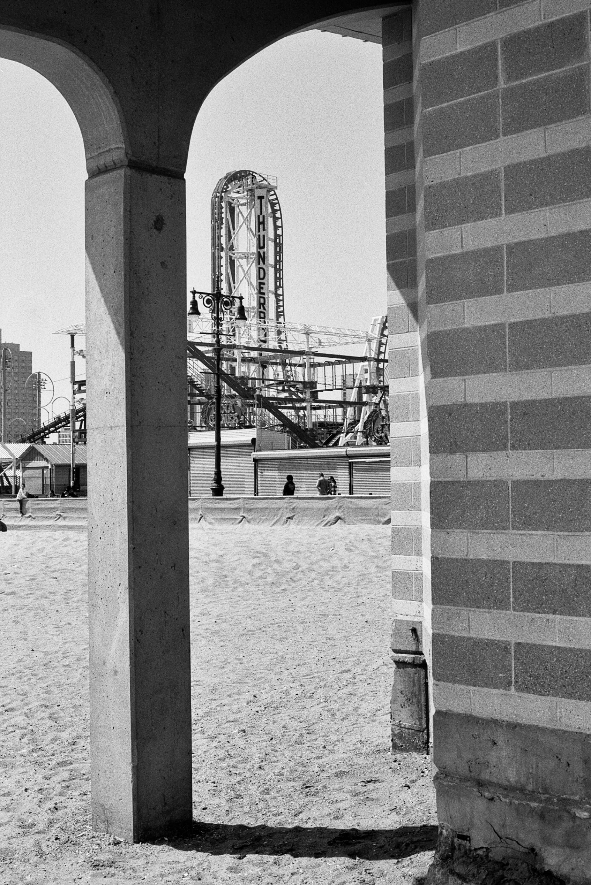 View of a roller coaster through an archway, capturing a dramatic black and white scene.