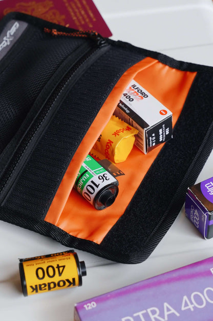 RETO Film X-Protec Bag (Medium) with 35mm film rolls inside, featuring a durable black exterior and vibrant orange lining.