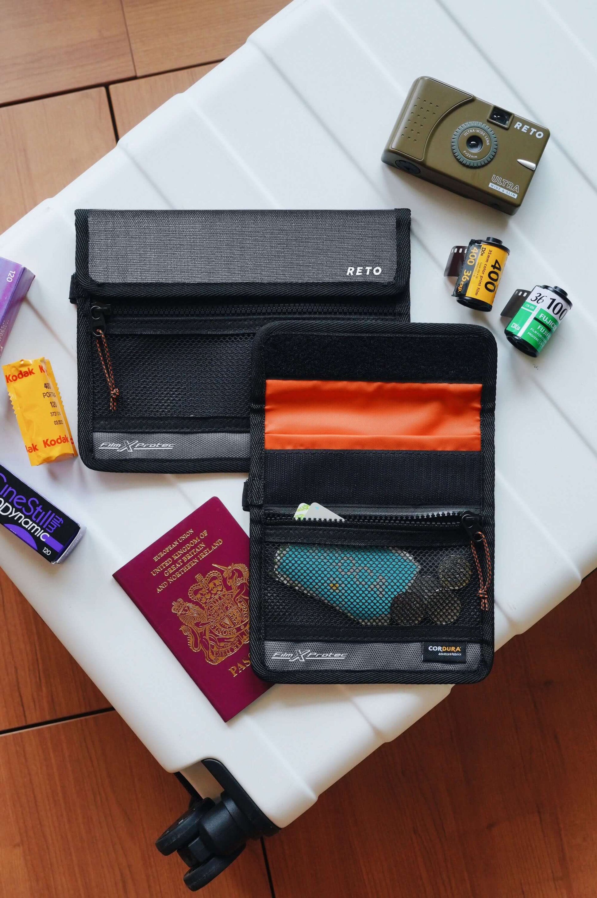 RETO Film X-Protec Bag (Small) alongside film rolls and a passport on a travel suitcase.