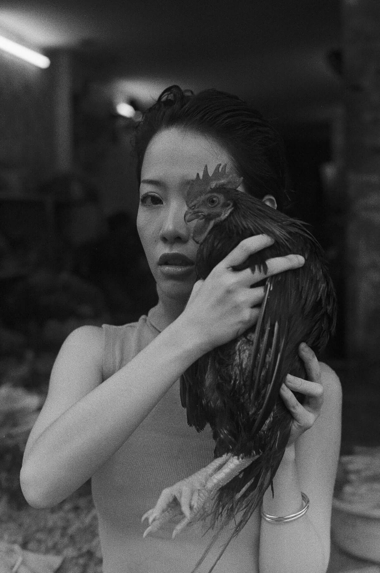 Black and white image of a woman holding a chicken, showcasing raw emotional expression and cultural connection shot on Mr Negative Black Market 250