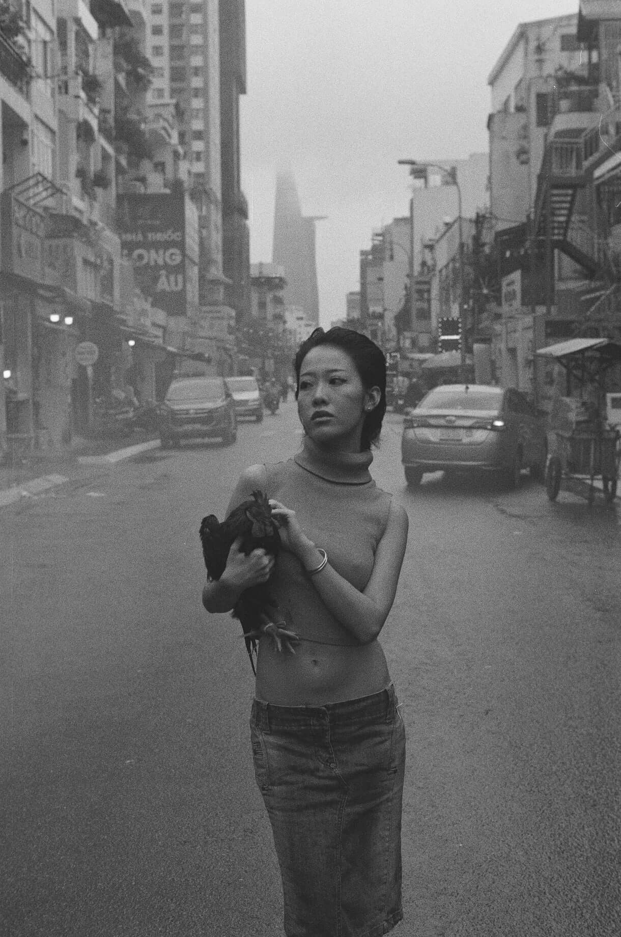 A woman in a black and white street scene holds a chicken, showcasing urban life shot on Mr Negative Black Market 250
