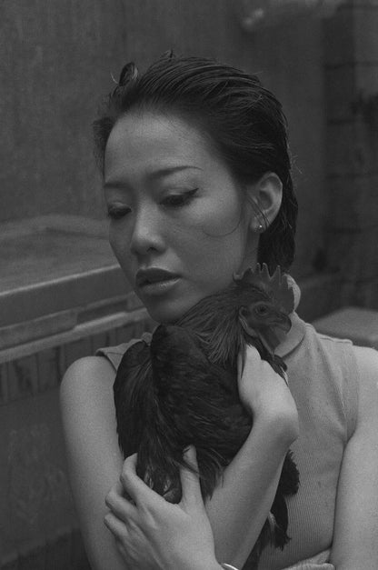 Black and white image of a woman holding a black chicken, conveying a sense of intimacy and contemplation. Shot on Mr Negative Black Market 250