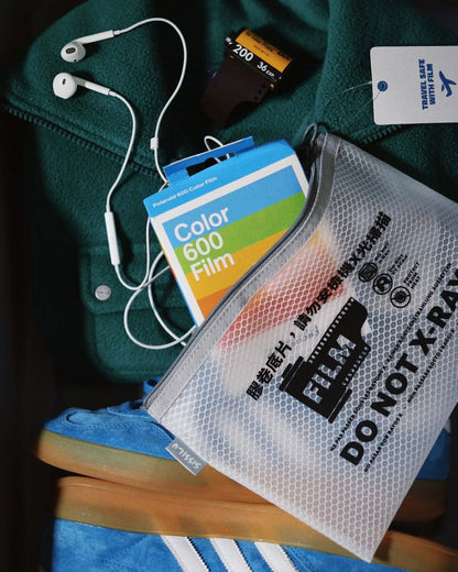SissiLu "DO NOT X‑RAY" Film Pouch with accessories including film and earphones on a green sweater.