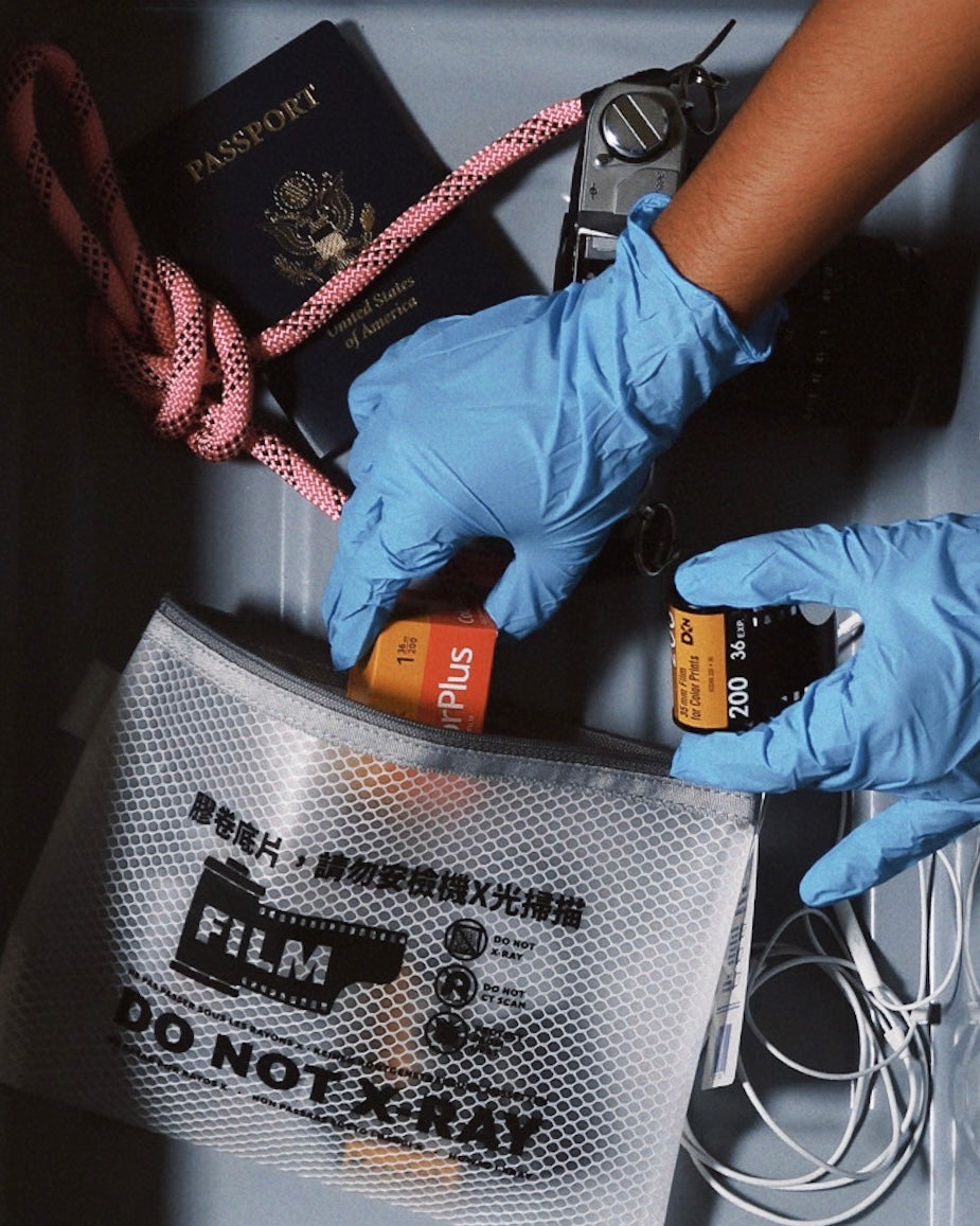 SissiLu "DO NOT X‑RAY" Film Pouch with undeveloped film, camera, passport, and gloves in a travel setup.