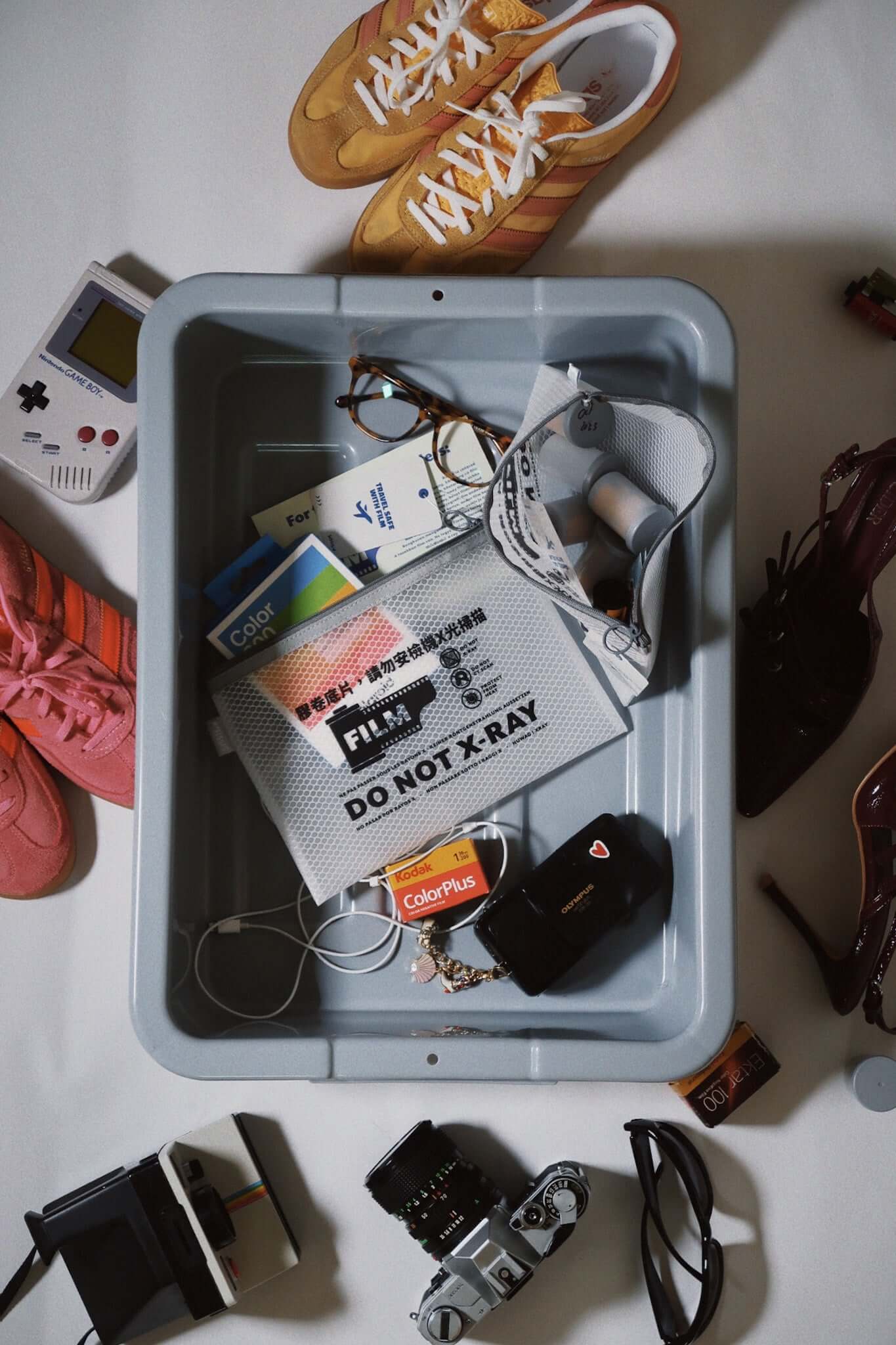 SissiLu "DO NOT X‑RAY" Film Pouch surrounded by travel items including shoes, glasses, and cameras.