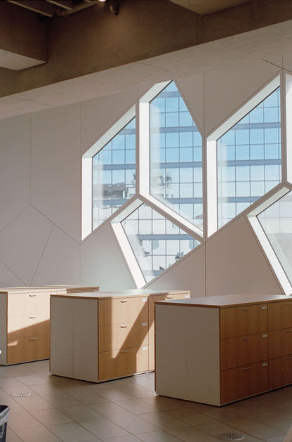 Modern office interior featuring unique geometric windows and wooden drawers.