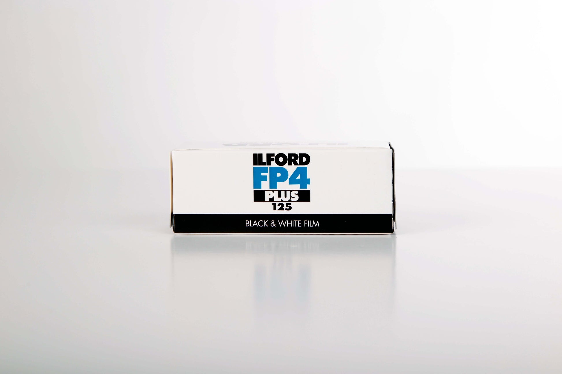Ilford FP4 Plus 125 black and white film box on a reflective surface, ideal for ISO 125 photography.