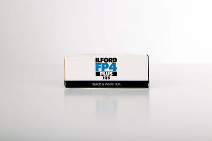 Ilford FP4 Plus 125 black and white film box on a reflective surface, ideal for ISO 125 photography.