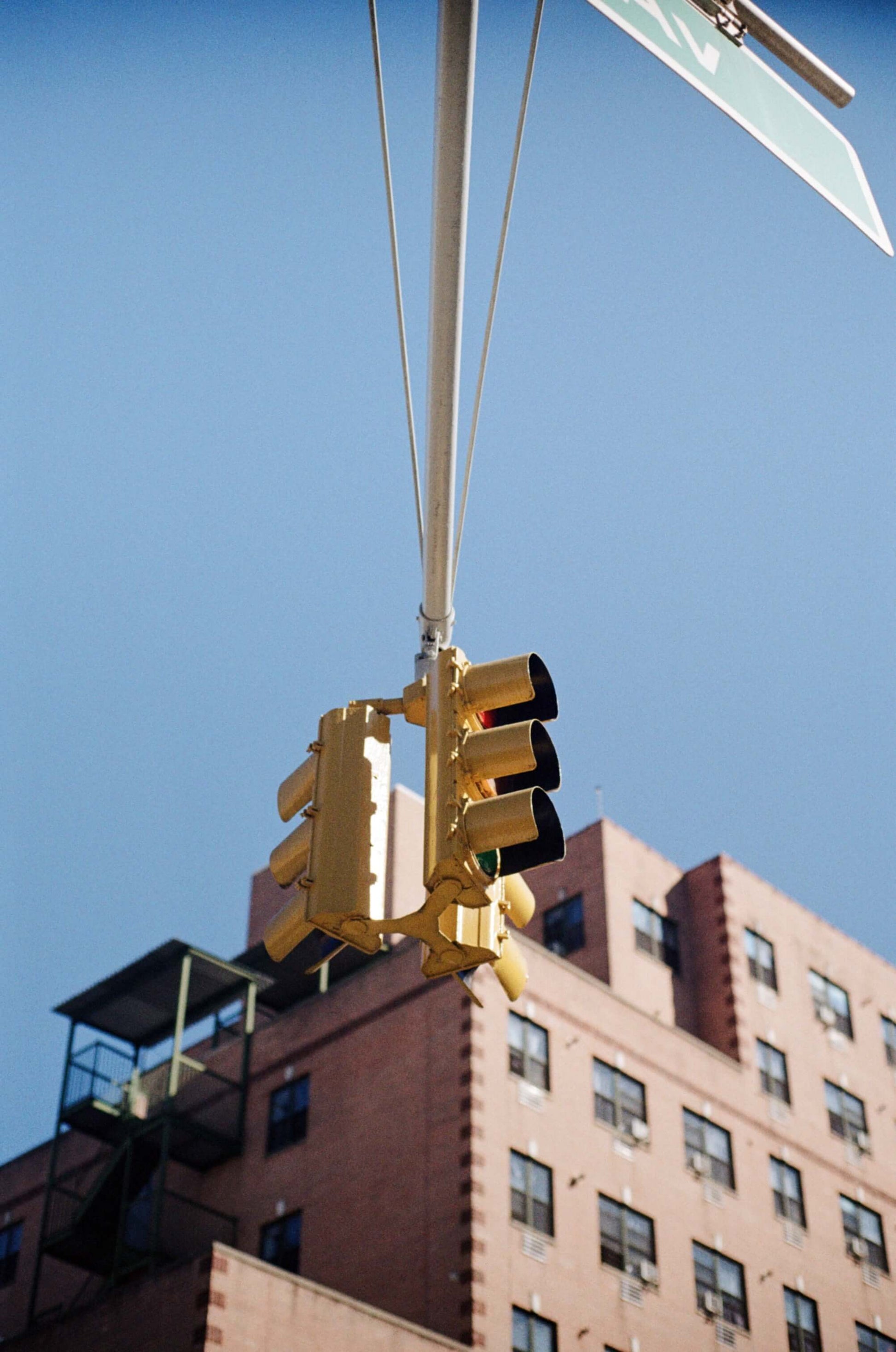 Yellow traffic light against a clear blue sky in an urban setting.