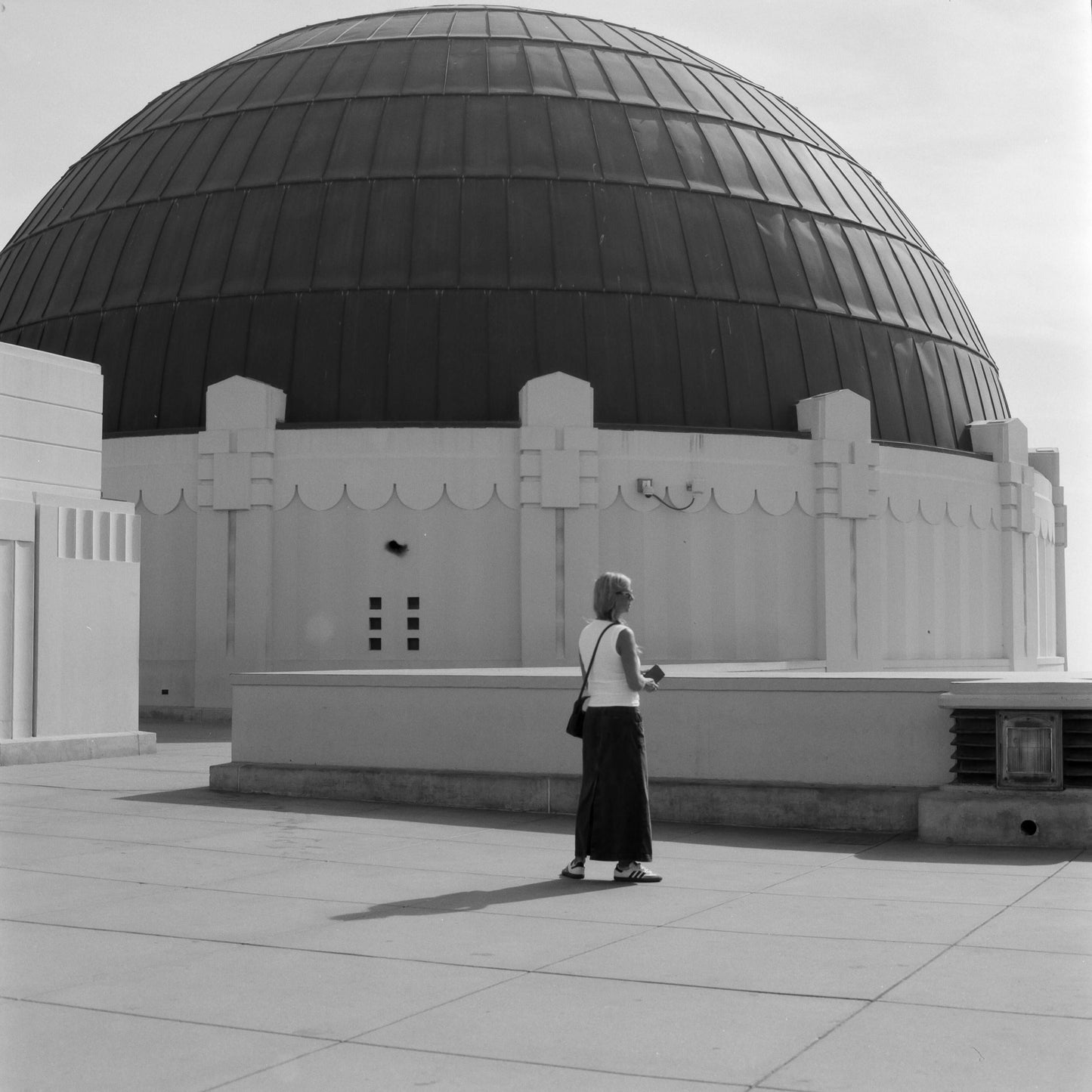 Person walking near a large domed building under a clear sky in black and white photograph, captured on Ilford Ortho Plus 80.