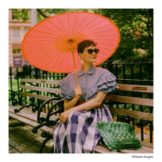 Woman seated on a bench with a bright orange parasol, capturing vibrant color with Harman Phoenix II 200 Color Negative Film (120 Roll Film).
