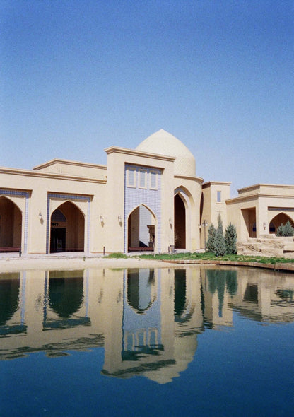 Beautiful architectural reflection of a building by the water under a clear blue sky.