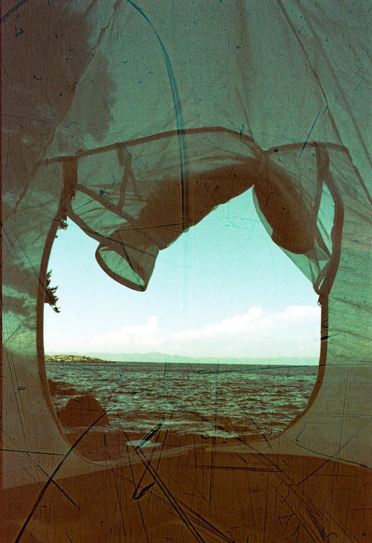 View of the sea through a tent, showcasing the vintage effect of Revolog Streak 200 Color Negative Film (35mm, 36 Exposures)