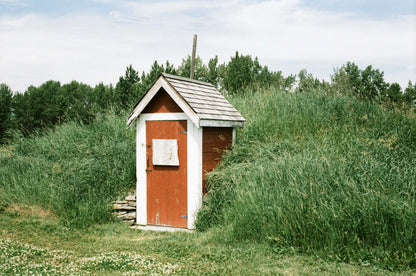 Street Candy Tasty 200 color negative film photo of a rustic red shed surrounded by tall grass.