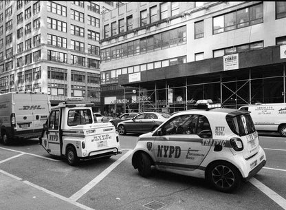 Black and white photograph of NYPD police and traffic vehicles on a city street.