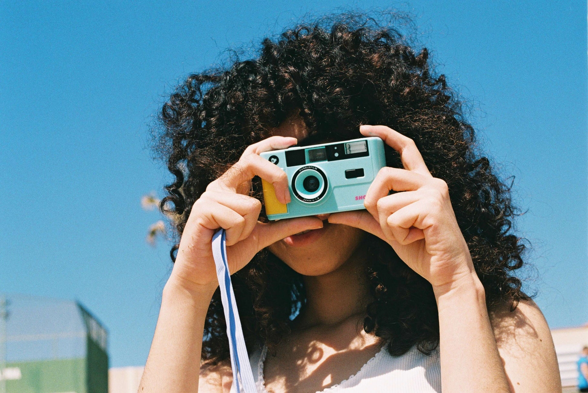 Dubblefilm SHOW 35mm Reusable Camera (Turquoise) - turquoise camera with built-in flash, handheld by a person, ready for on-the-go photography